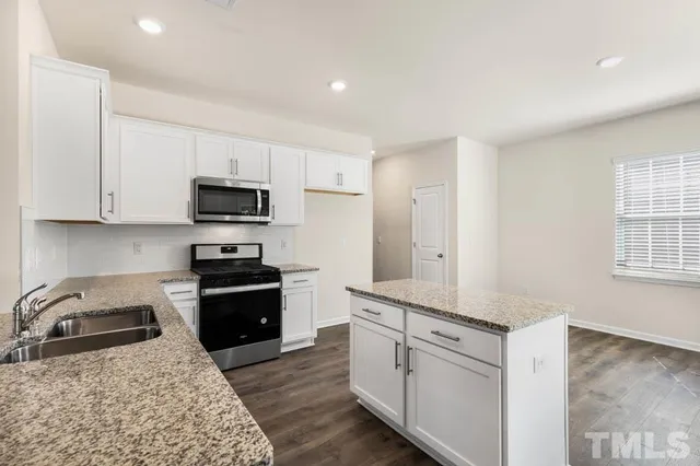 a kitchen with a sink a stove top oven a refrigerator and white cabinets