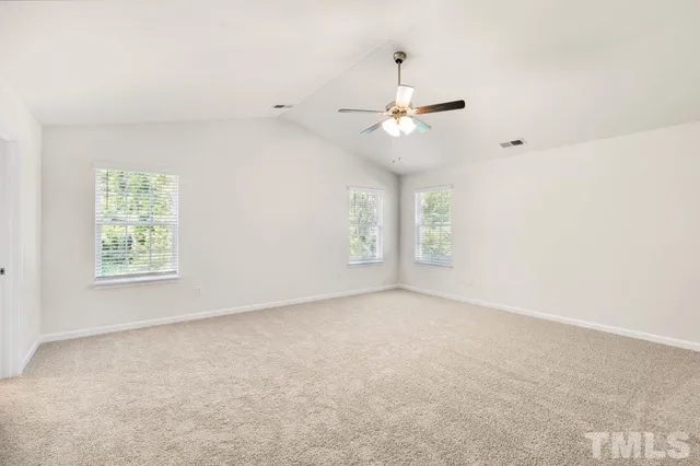 an empty room with windows and fan