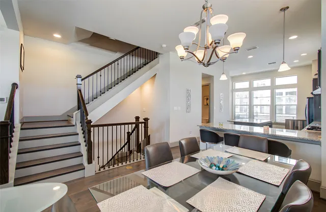 a kitchen with stainless steel appliances granite countertop a table chairs stove and refrigerator