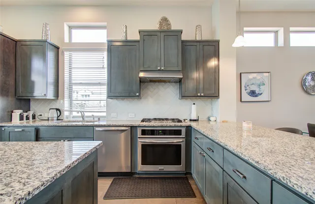 a kitchen with granite countertop a sink a counter top stainless steel appliances and cabinets