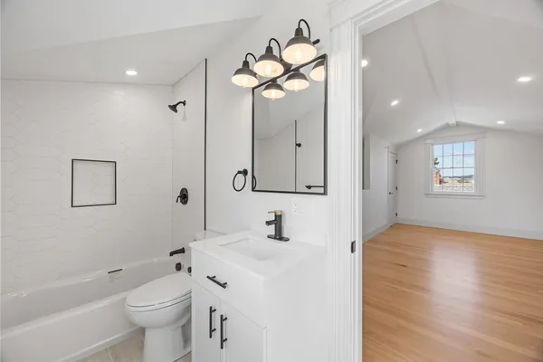 a bathroom with a toilet a sink a mirror a bathtub and vanity