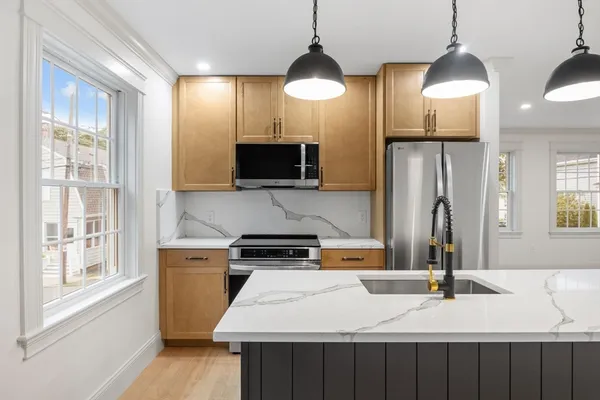 a kitchen with stainless steel appliances a stove a refrigerator a sink and a wooden floor