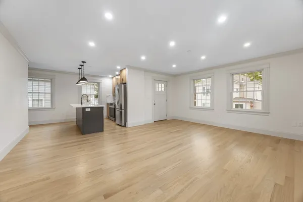 an empty room with windows and kitchen view