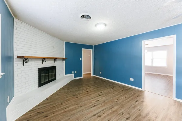 an empty room with wooden floor fireplace and windows