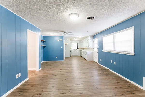 a view of an empty room with window and wooden floor