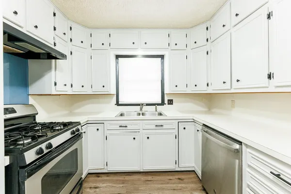 a kitchen with white cabinets and appliances