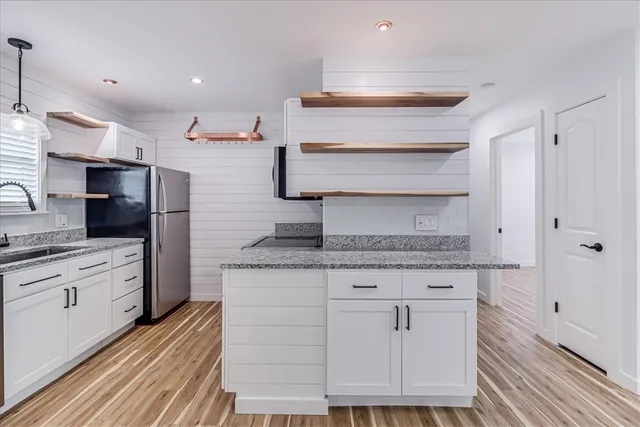 a kitchen with stainless steel appliances cabinets and a wooden floor
