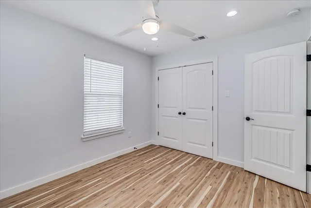 a view of empty room with wooden floor and fan