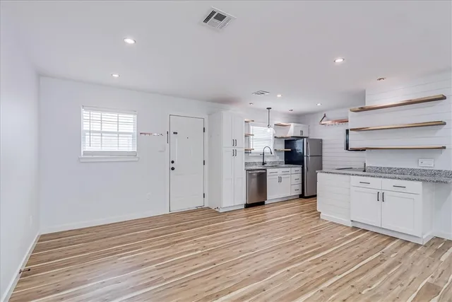 a kitchen with granite countertop white cabinets and stainless steel appliances