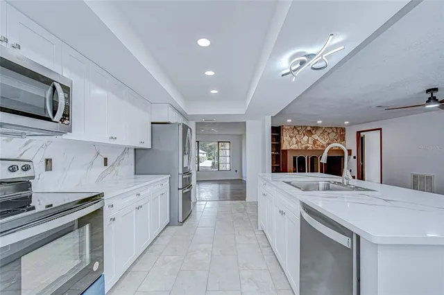 a large white kitchen with stainless steel appliances granite countertop a stove and a sink
