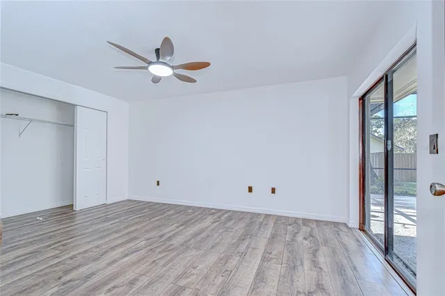 a view of empty room with wooden floor and fan
