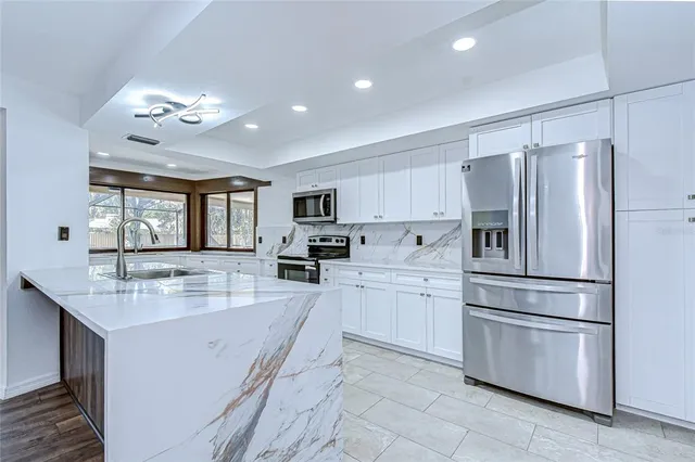 a large kitchen with kitchen island a sink stainless steel appliances and cabinets