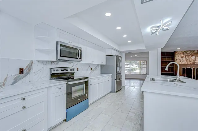 a kitchen with a sink stainless steel appliances cabinets and a window