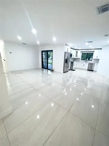 a view of empty room with kitchen and window