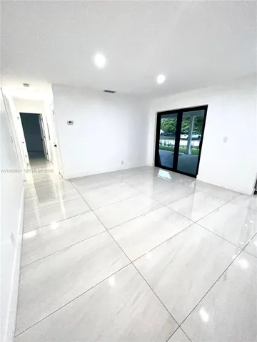a view of a livingroom with wooden floor and a refrigerator