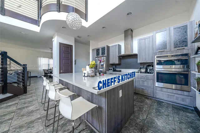 a kitchen with stainless steel appliances granite countertop a stove top oven a sink dishwasher a dining table and chairs with wooden floor