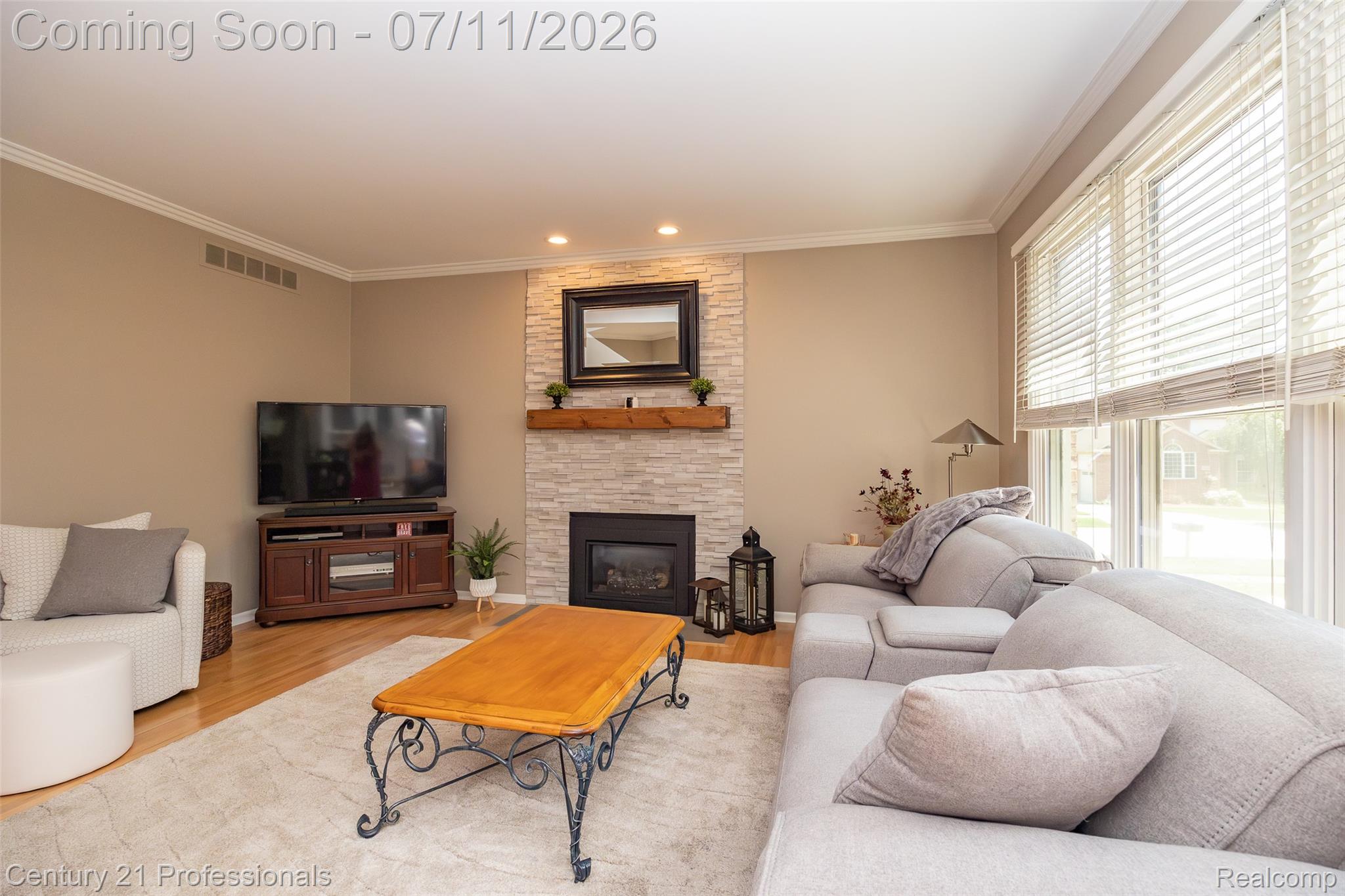 689 Woodfield Way Rochester, MI 48307 - Photo 50 of 61 Living area featuring a stone-faced fireplace with a wood mantle, recessed lighting, crown molding, and light wood-finish flooring