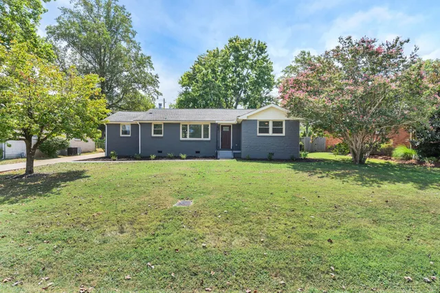 a view of house with yard and trees in the background