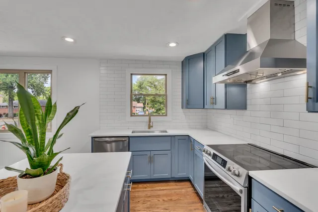 a kitchen with stainless steel appliances granite countertop a stove a sink and a white cabinets