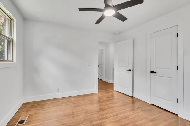 a view of an empty room with wooden floor and a window