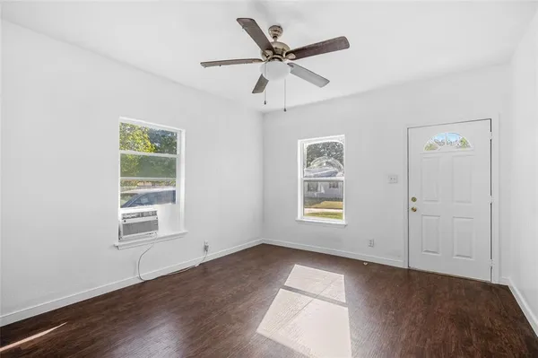 a view of an empty room with a window and wooden floor