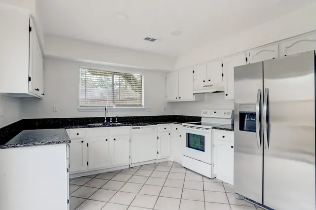 a kitchen with granite countertop white cabinets and white appliances