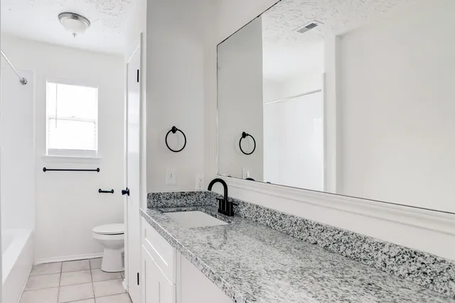 a bathroom with a granite countertop sink a toilet and a shower