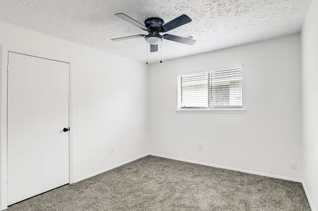 an empty room with a window and a ceiling fan