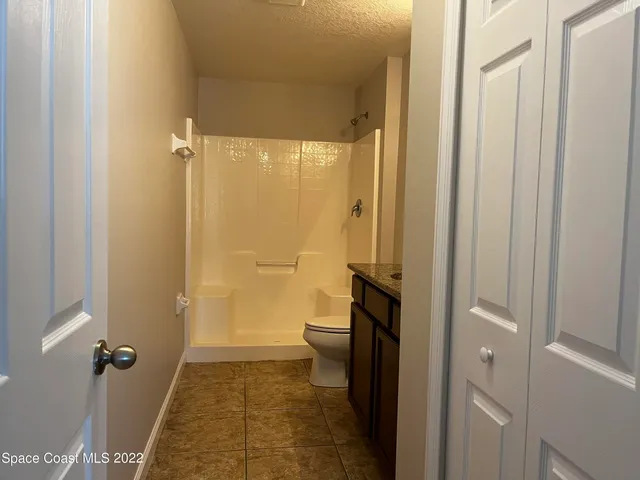 a bathroom with a granite countertop toilet a sink and shower