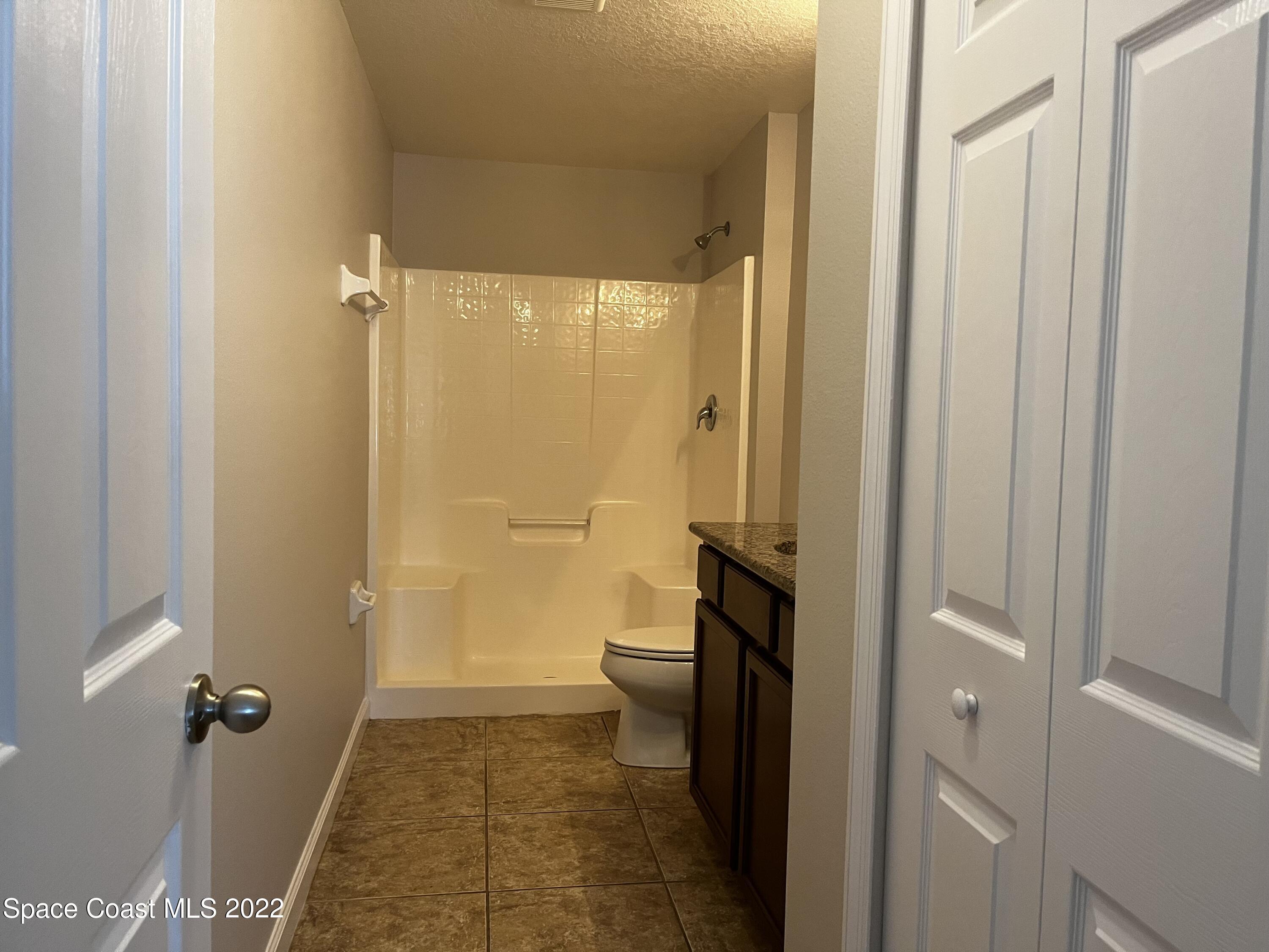 4127 Meander Place, Unit 203 Rockledge, FL 32955 - Photo 11 of 13 a bathroom with a granite countertop toilet a sink and shower