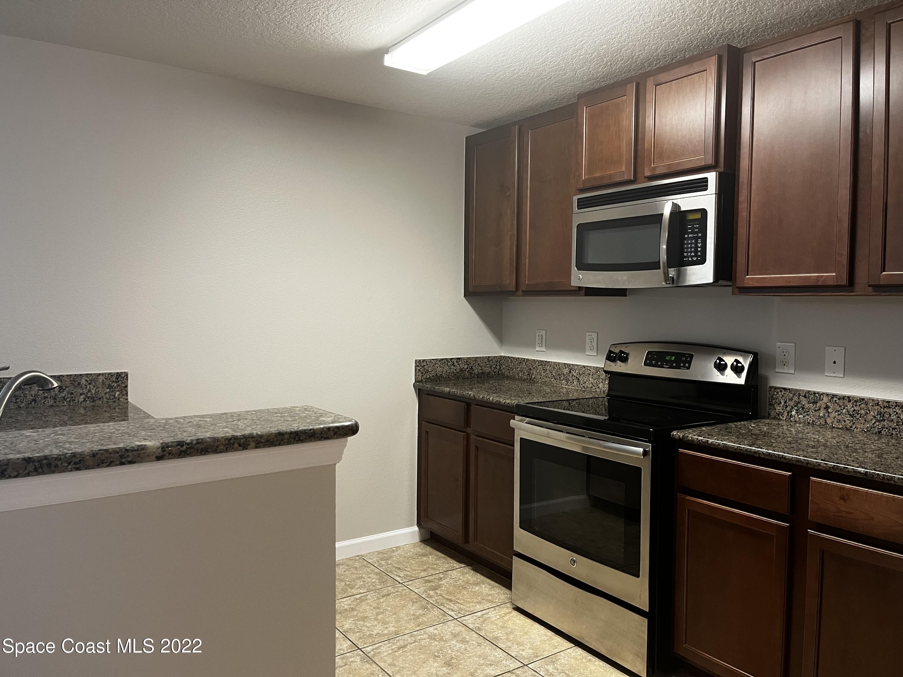 4127 Meander Place, Unit 203 Rockledge, FL 32955 - Photo 2 of 13 a kitchen with granite countertop stainless steel appliances and wooden cabinets