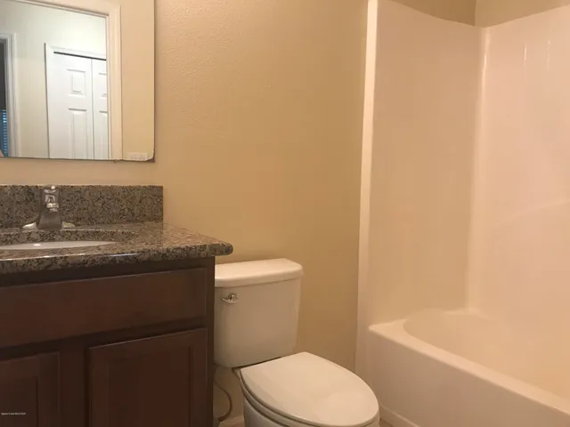 a bathroom with a granite countertop toilet sink and mirror