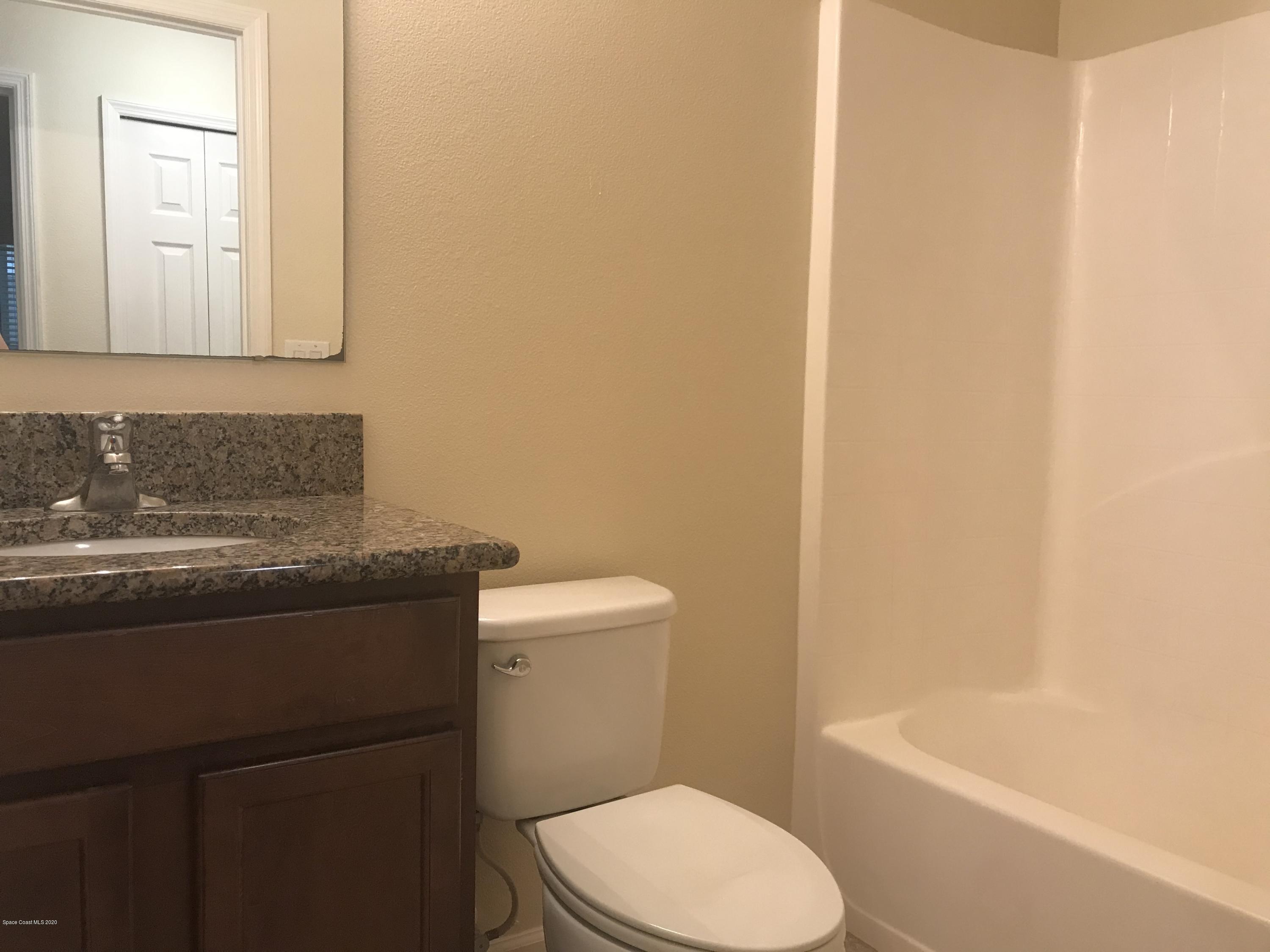 4127 Meander Place, Unit 203 Rockledge, FL 32955 - Photo 4 of 13 a bathroom with a granite countertop toilet sink and mirror