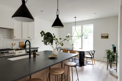 a kitchen with stainless steel appliances granite countertop a sink a stove and chairs