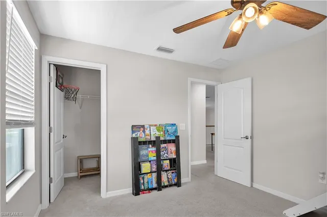 a view of an empty room with window and chandelier fan