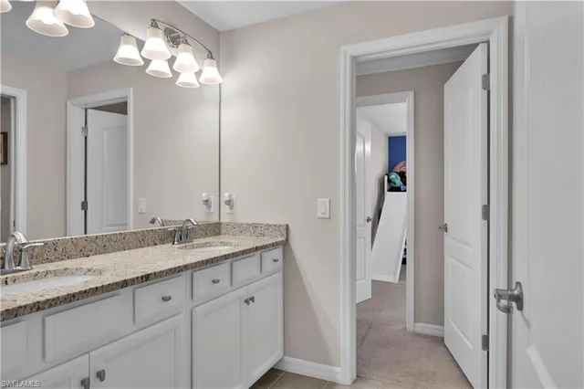 a bathroom with a granite countertop sink a light fixture and a mirror