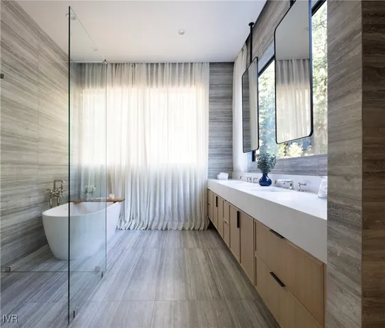 a bathroom with a double vanity sink a large mirror a bathtub and next to a window