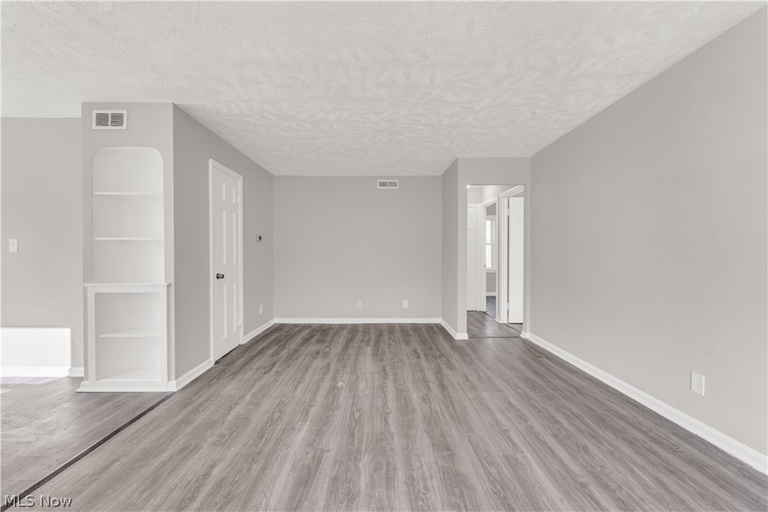 2521 Greenvale Road Cleveland, OH 44121 - Photo 5 of 23 Living area featuring wood-finish flooring, light gray wall paint, white baseboards, and a built-in shelving unit