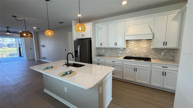 a kitchen that has a lot of white cabinets and stainless steel appliances