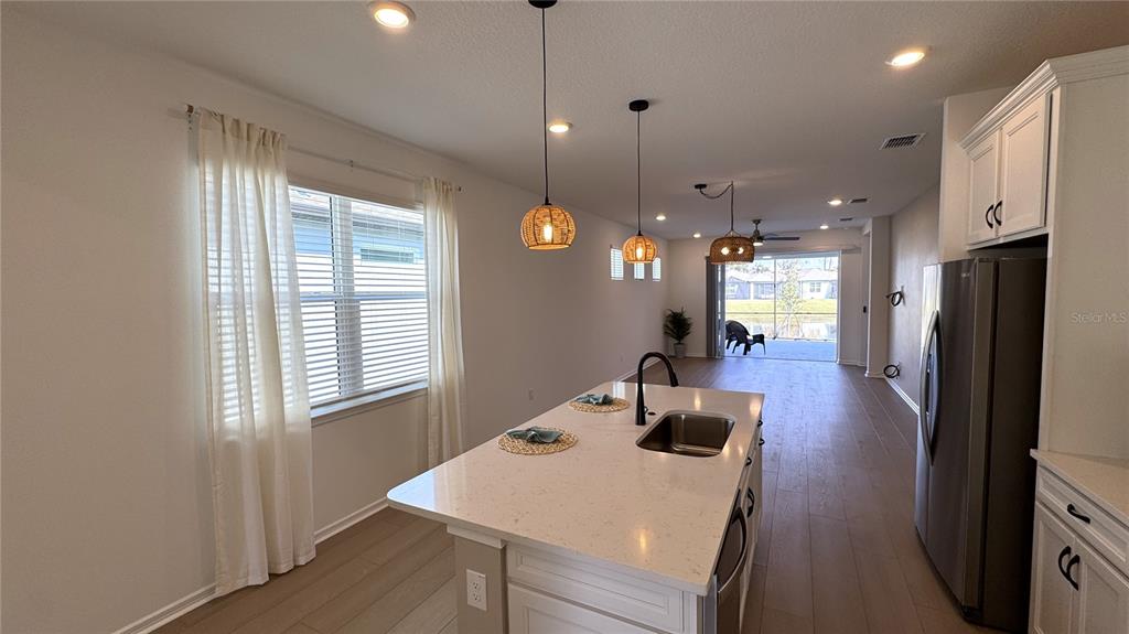 9408 Coastline Way Palmetto, FL 34221 - Photo 7 of 41 a kitchen with stainless steel appliances kitchen island granite countertop a refrigerator a stove a sink dishwasher and a dining table with wooden floor