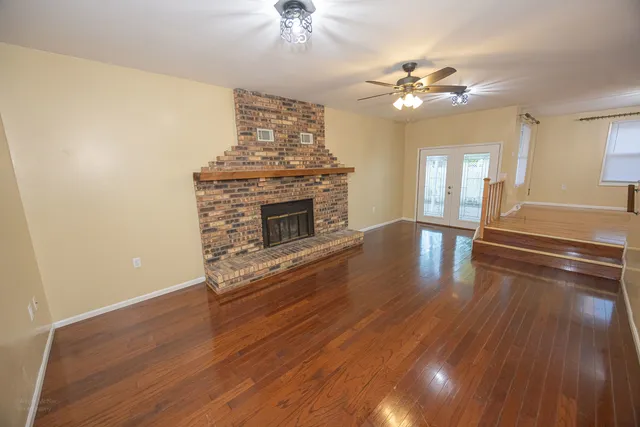 a view of a livingroom with wooden floor a ceiling fan and staircase