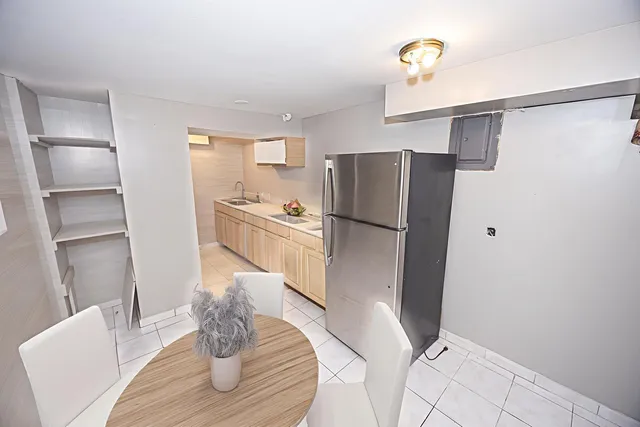 a kitchen with a refrigerator a stove and a dining table with wooden floor