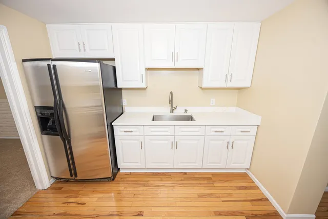 a kitchen with white cabinets and refrigerator