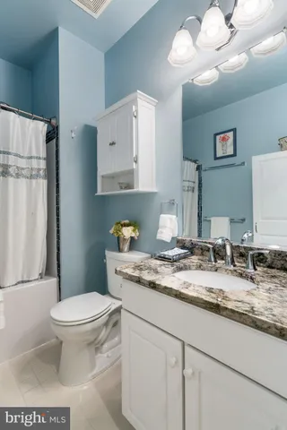 a bathroom with a granite countertop toilet sink and mirror