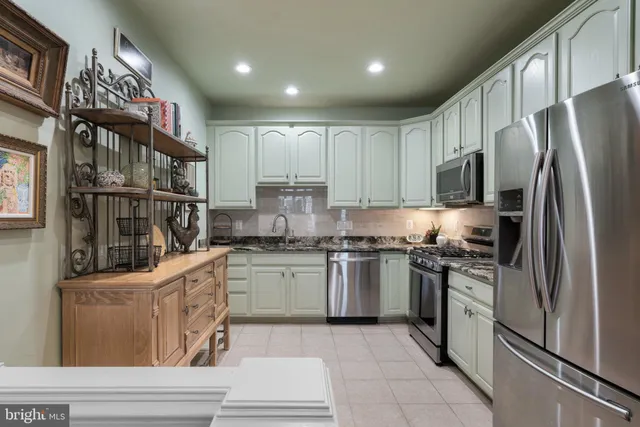 a kitchen with stainless steel appliances granite countertop a refrigerator a stove and a sink