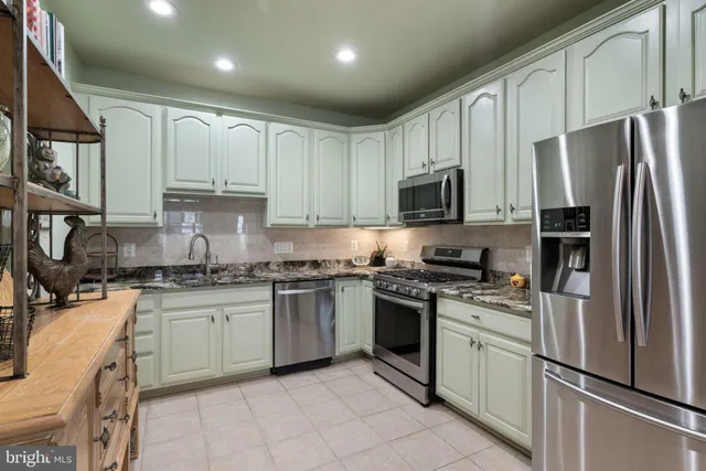 a kitchen with stainless steel appliances granite countertop a stove top oven a refrigerator a sink and dishwasher