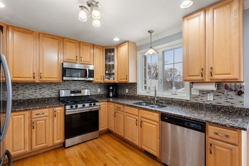 21 Hartwell Place, Unit 21 Canton, MA 02021 - Photo 5 of 33 a kitchen with stainless steel appliances granite countertop wooden cabinets a sink a stove a window and cabinetry