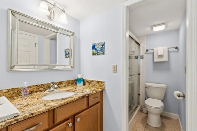 a bathroom with a granite countertop sink toilet mirror and shower