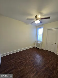 a view of a room with wooden floor and a ceiling fan