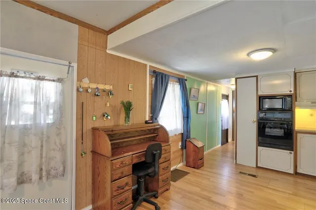 a kitchen with white cabinets and wooden floor